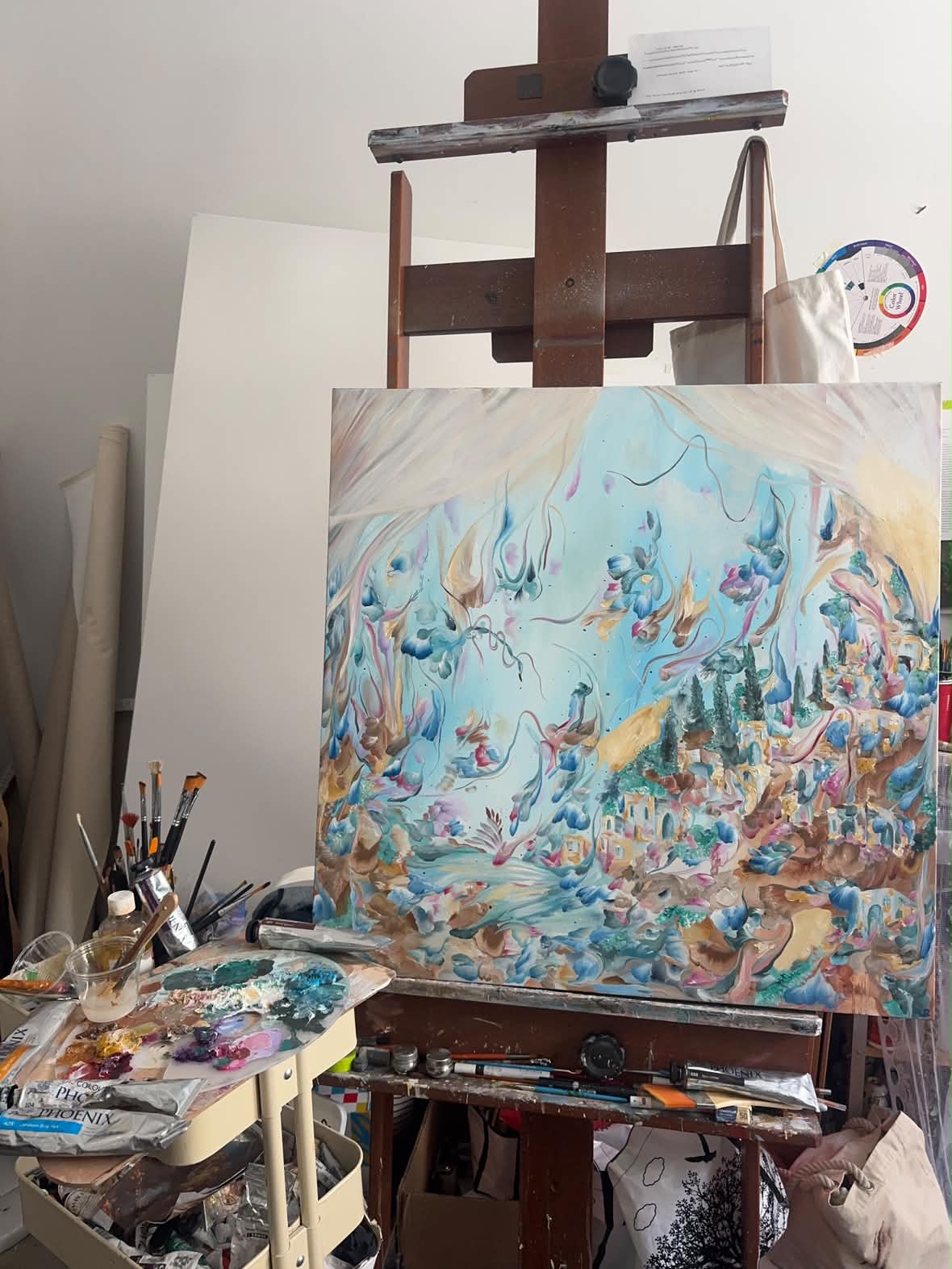 Aqua-toned oil painting on a studio easel with the artist’s palette and PHOENIX tubes below.